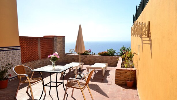 A patio with a table and chairs, a potted plant, and a view of the sea. - Casa Junonia Apartments, with terrace, Bajo C (Playa de Santiago)