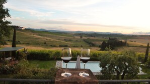 A terrace with two wine glasses and a table, overlooking a scenic landscape with hills and a pool. - Luxury Villa in Montepulciano - Private Heated Pool, Free WiFi, Magnificent view (Montepulciano)