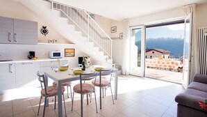 A modern kitchen with a dining area, a staircase, and a balcony with a mountain view. - Lenno Spese II –Village apartment In Lenno with pool by Italian Apartments. (Lenno)
