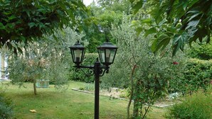 A garden with a black metal lamp post and two lanterns.