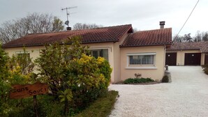A house with a gravel driveway, a satellite dish, and a sign reading "Sans Souci".