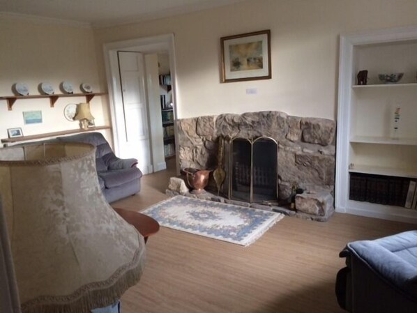 A living room with a stone fireplace, a blue sofa, a patterned rug, and a lamp. - Beautifully situated amidst rolling farmland (Scotland)