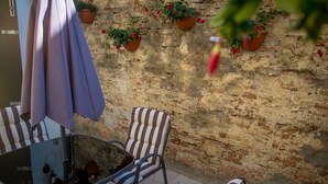A patio with striped chairs and a table, potted plants on a brick wall, and a hanging umbrella. - bright apartment fully restored (murano)