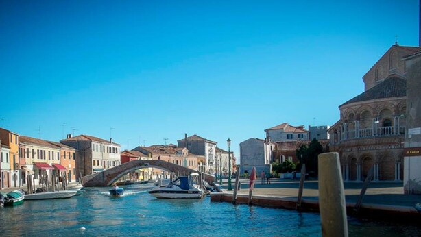 A canal with boats, a bridge, and historic buildings. - bright apartment fully restored (murano)