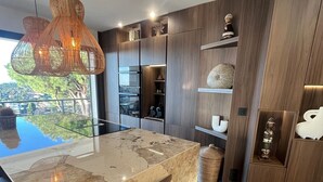 Una cocina moderna con una isla de mármol, armarios de madera e iluminación colgante.