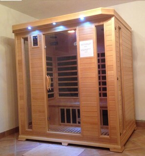 Un sauna en bois avec une porte en verre, un panneau de commande et une pancarte sur la porte.