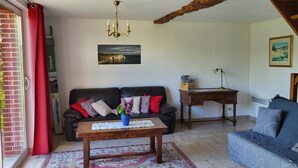 En stue med en sofa, et sofabord med en vase, et skrivebord og en lampe.