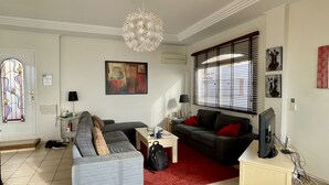 Un salon avec un canapé, une table basse, un téléviseur et un tapis rouge.