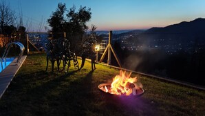Una piscina, un foc i una vista a una ciutat al capvespre.
