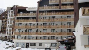 A multi-story hotel with balconies, a ski lift, and a snowy landscape.
