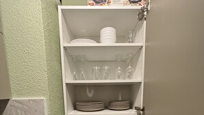 A kitchen with white cabinets, a trash bin, and a box labeled "TEFAL Raclette-Grill".