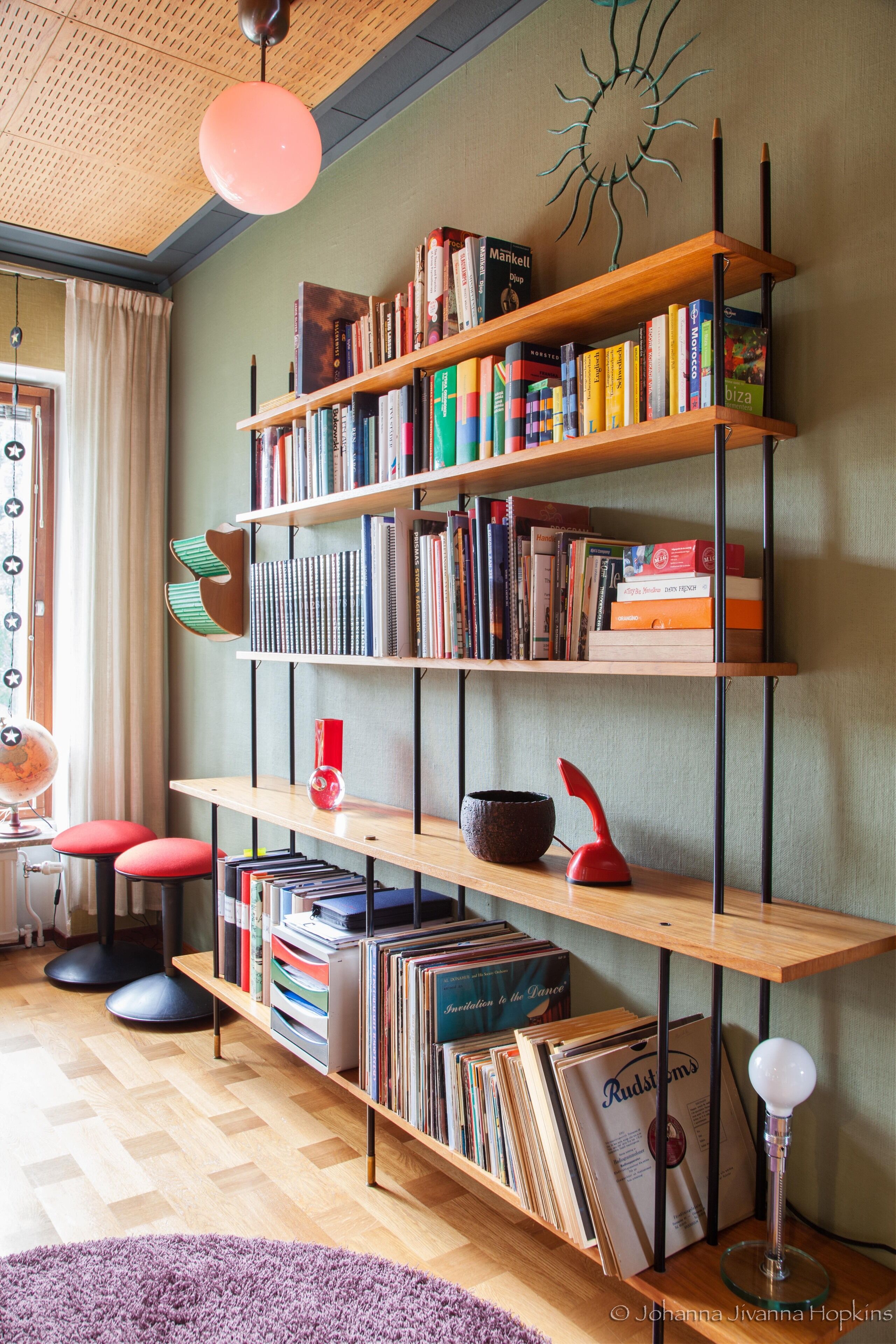 A room with a bookshelf filled with books, a globe, and a desk lamp.