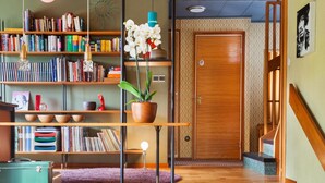 A modern interior with a wooden staircase, a bookshelf filled with books, a potted plant, and a vintage suitcase. - 60ies house in Stockholm close to nature, International Fairs, S-malm and City (Stockholm)