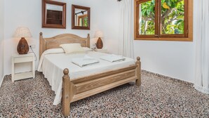 Ein Schlafzimmer mit einem hölzernen Bett, zwei Nachttischen mit Lampen, einem Fenster mit Vorhängen und einem Spiegel an der Wand.
