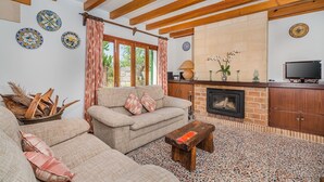 Ein Wohnzimmer mit Sofa, Couchtisch und Kamin. An der Wand befinden sich dekorative Teller und ein Fernseher steht auf einem Schrank.
