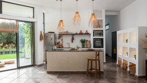 A modern kitchen with a large island, pendant lights, and a view to a garden. - House / Villa - MarrakechHouse with garden (Marrakesh)