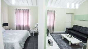 Een slaapkamer met een bed, een stoel, een bank, een televisie en een bijzettafeltje.