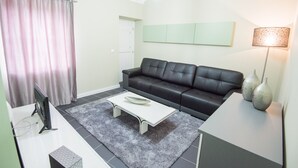 Een moderne woonkamer met een zwarte leren bank, een witte salontafel en een grijze vloerkleden.