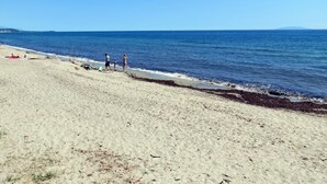 Una playa con gente tomando el sol y paseando por la orilla.