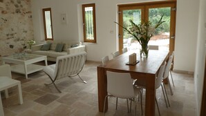 A modern living room with a white sofa, a glass coffee table, and a dining area with a wooden table and white chairs. - Architecturally Designed Sea View Villa in Carovigno, Nr Ostuni with Heated Pool (carovigno)