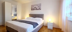 Un dormitorio ordenado con cama, mesitas de noche, un armario y un cuadro en la pared.
