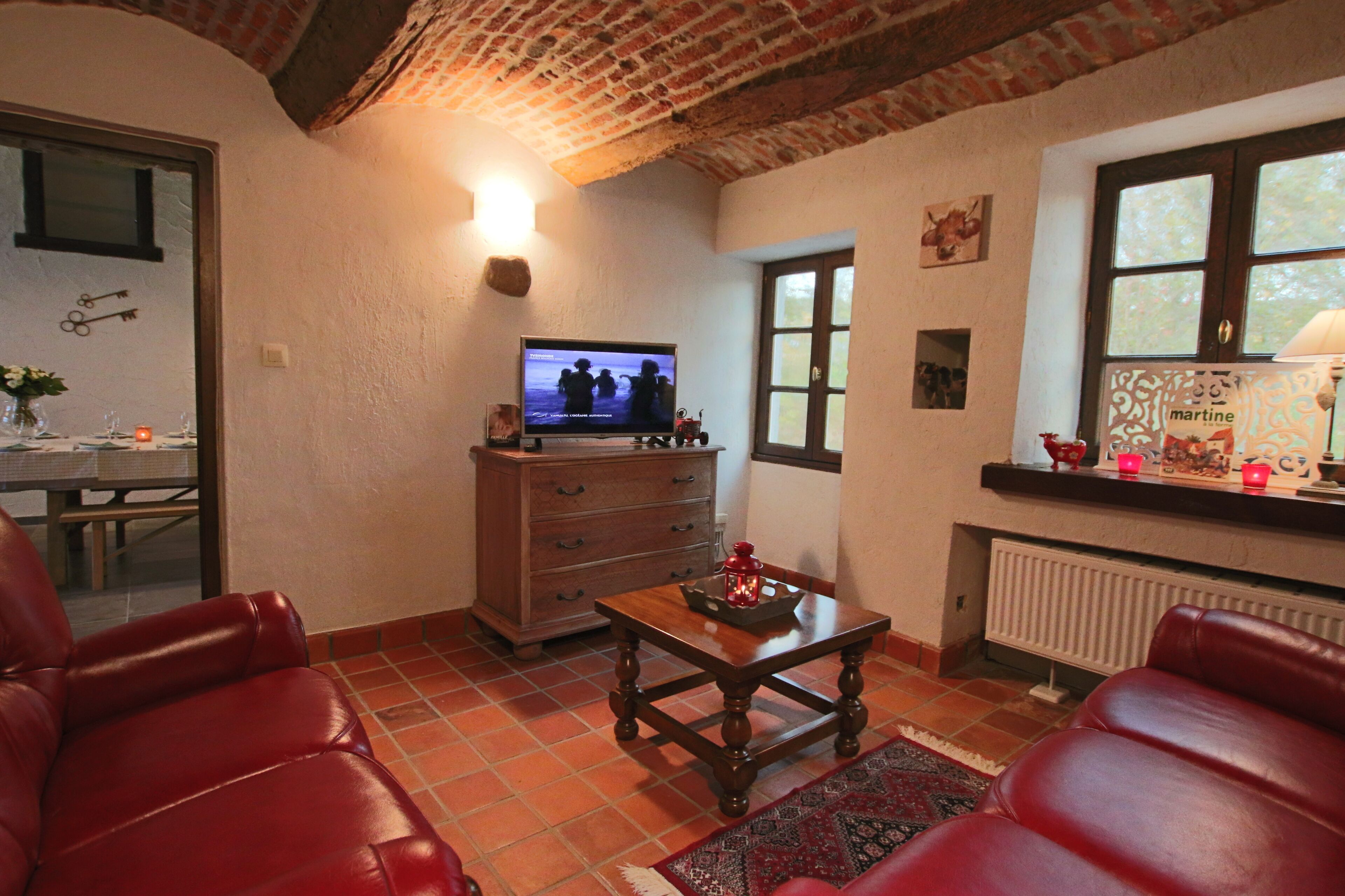 Ein gemütliches Wohnzimmer mit Kamin, Ledersesseln, einem Holztisch und einem Fernseher.
