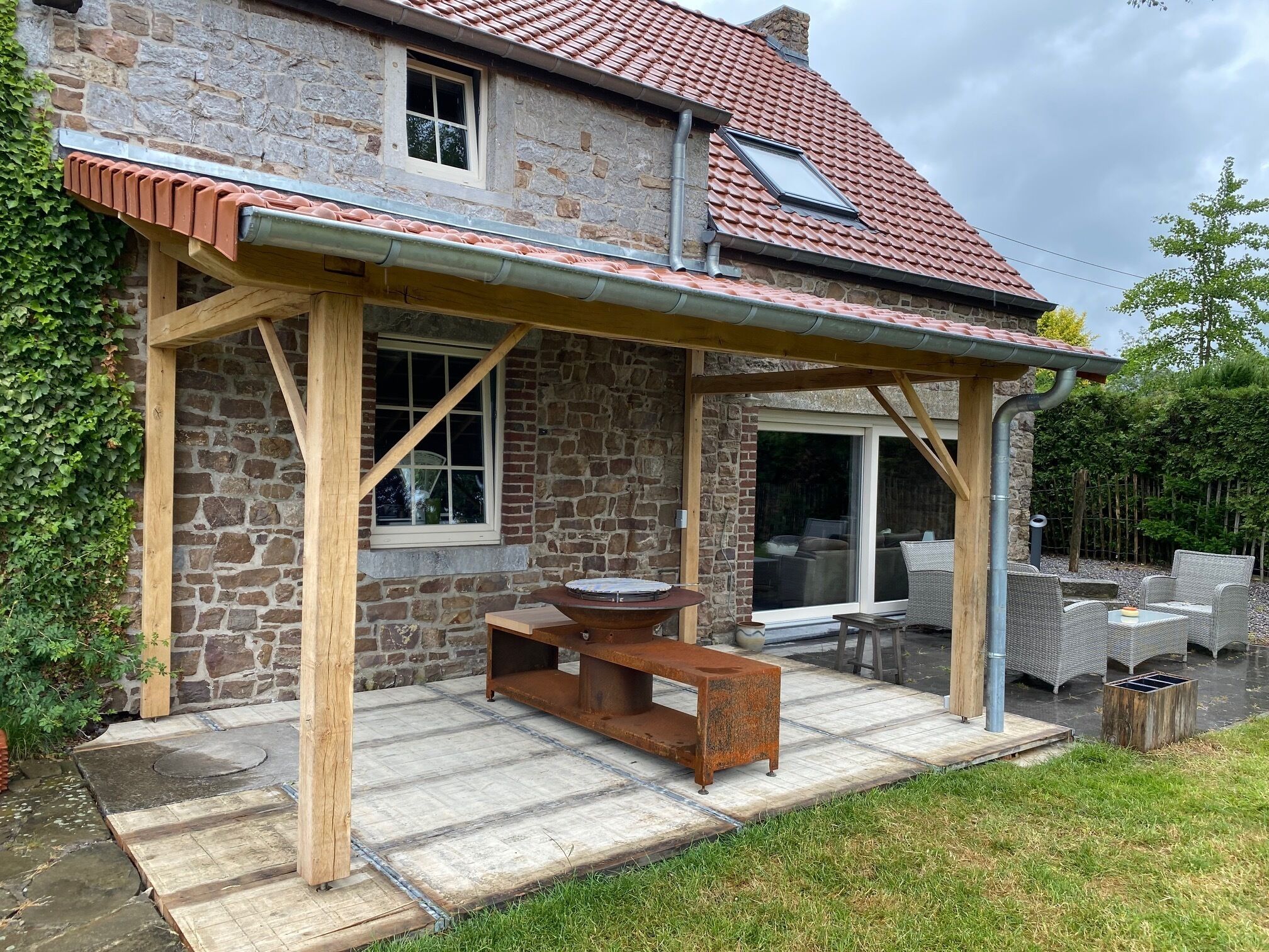 A stone house with a covered patio, a wooden bench, and outdoor furniture.