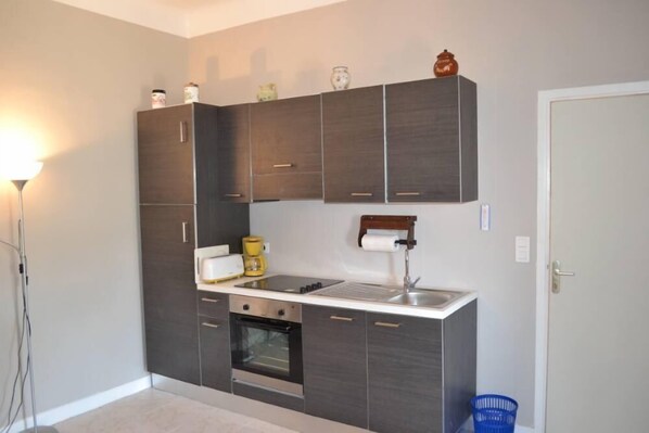 A compact kitchen with dark cabinetry, a built-in oven, a sink, and a countertop with a kettle and a coffee maker. - Between Monaco & St Jean Cap Ferrat, Eze bord de Mer, 200 m from the beach (Èze)