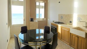 A compact kitchen with a round table, chairs, a stove, and a sink. - Large apartment for exclusive use on the sea (Trapani)
