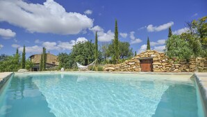 A clear swimming pool with a hammock and stone walls, surrounded by trees and a house. - Ancient Mint center Sicily (Pietraperzia (EN) Sicili)
