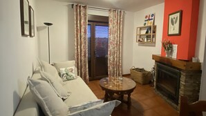 Una sala de estar con sofá, mesa de centro, chimenea y una puerta con cortinas.