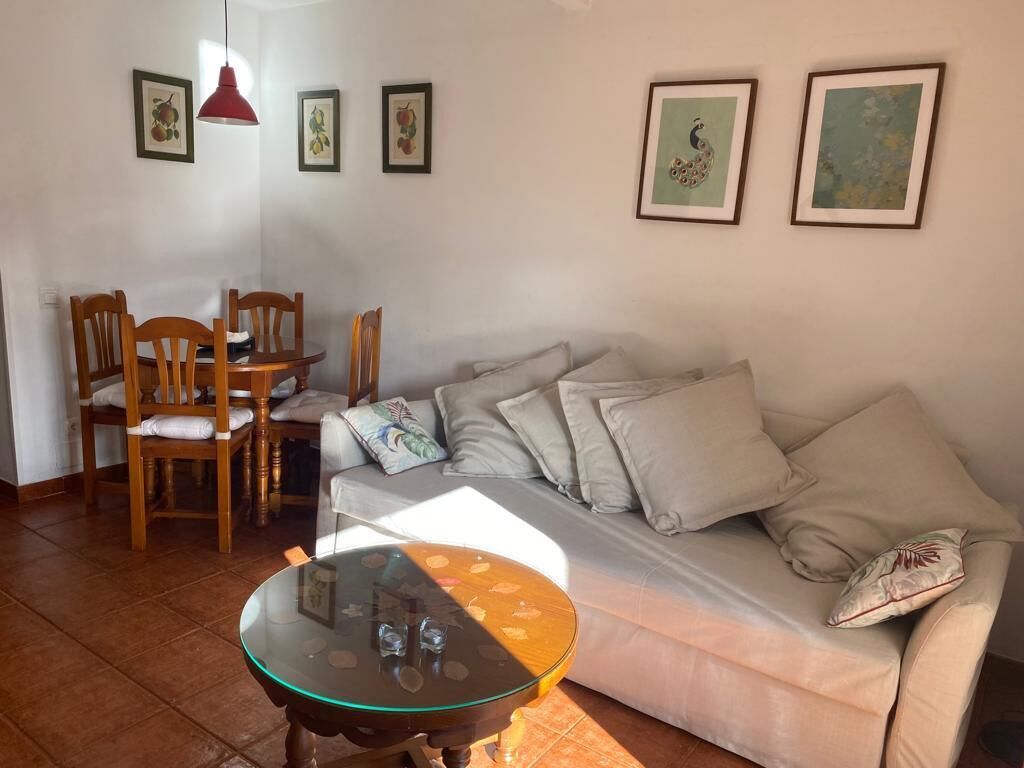 Un salon comprenant un canapé, une table basse en verre et un coin repas avec des chaises et une table.