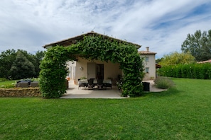 A house with a covered patio, a stone wall, and a well-maintained lawn.