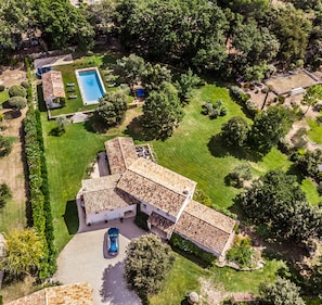 An aerial view of a property with a swimming pool, a covered patio, and a well-maintained lawn.