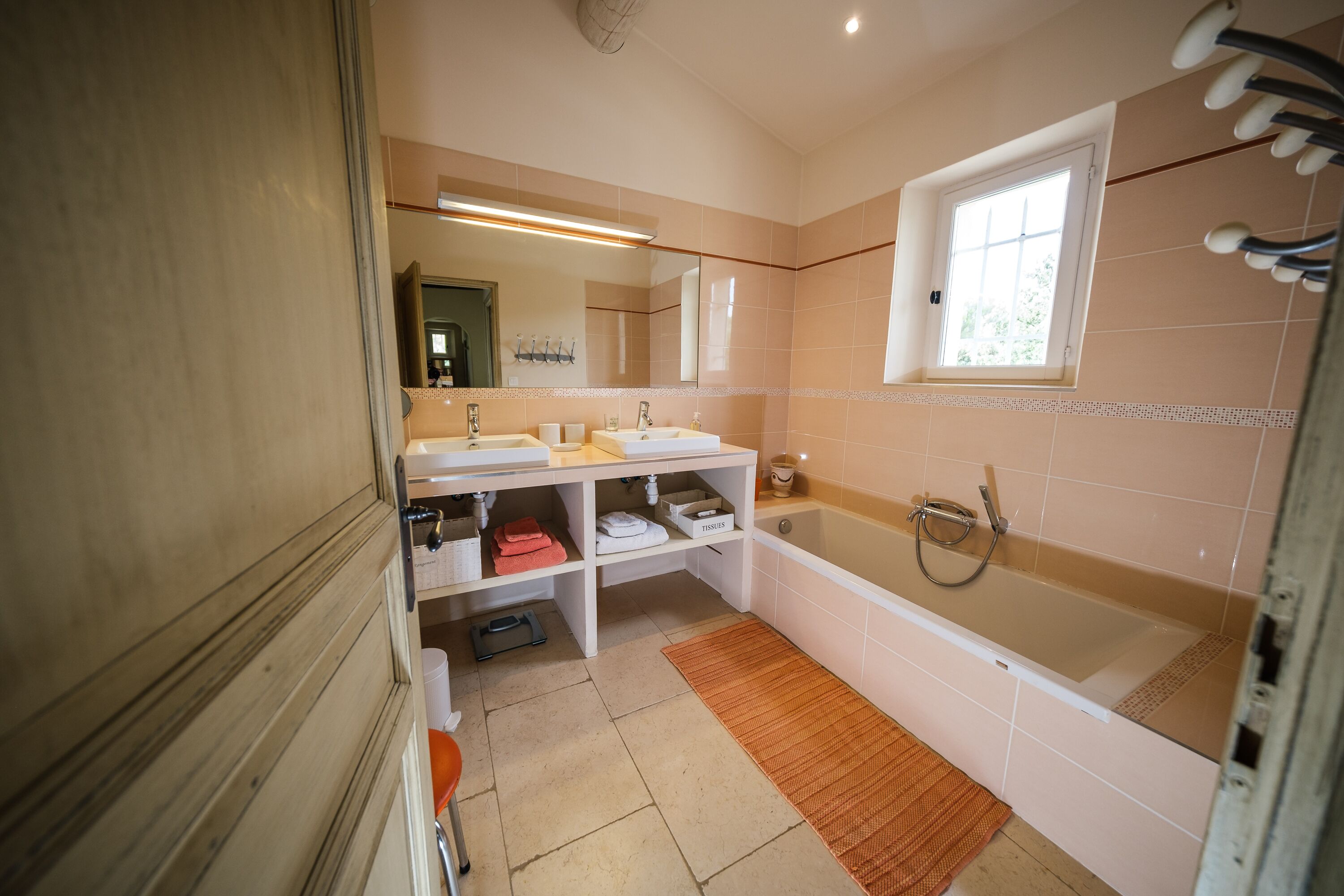Un baño con una bañera grande, dos lavamanos, una ventana y un espejo.