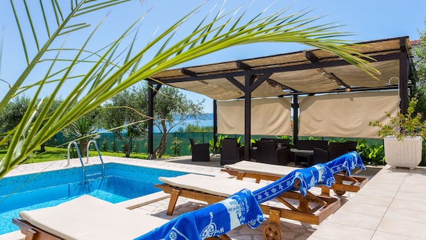 A poolside area with lounge chairs and a covered seating area. - Luxury Villa With Pool, Gym, Bicycles And Beautiful Sea View (Kaštel Sucurac)