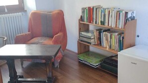 A living room with a wooden floor, a sofa, a coffee table, a bookshelf, and a radiator. - Bianchina💕 (premeno)