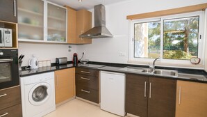 Eine moderne Küche mit Waschmaschine, Geschirrspüler und einem Fenster mit Blick auf Grünflächen.