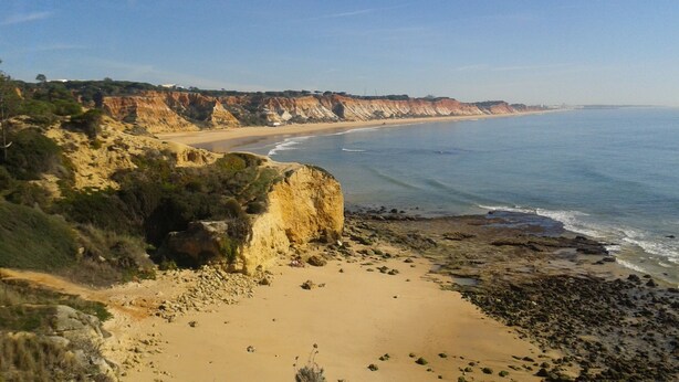 Eine Küstenlandschaft mit Sandstrand, Felsen und freiem Blick auf den Ozean.