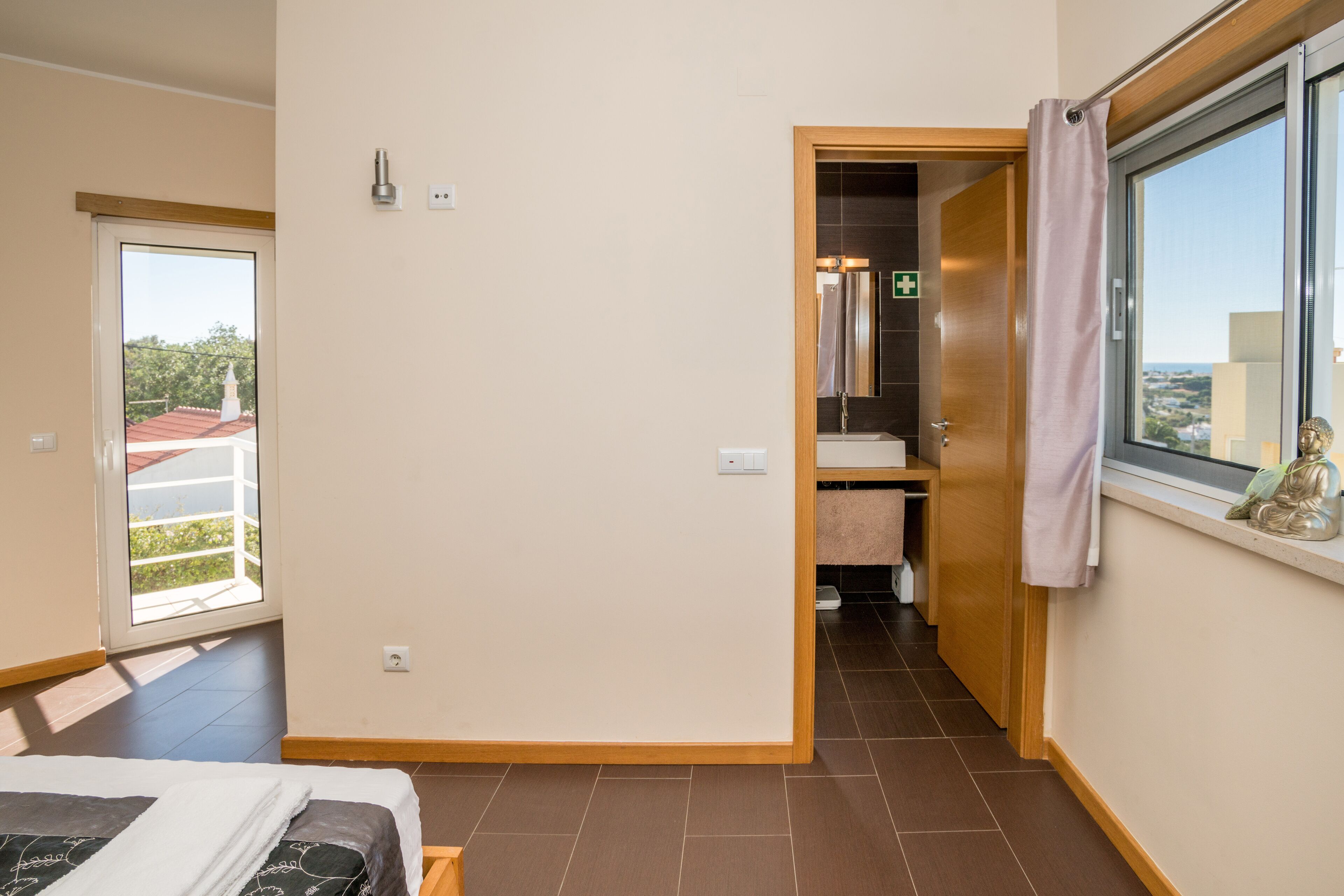 A hotel room with a bed, a bathroom with a mirror, and a window with a view of the outside.