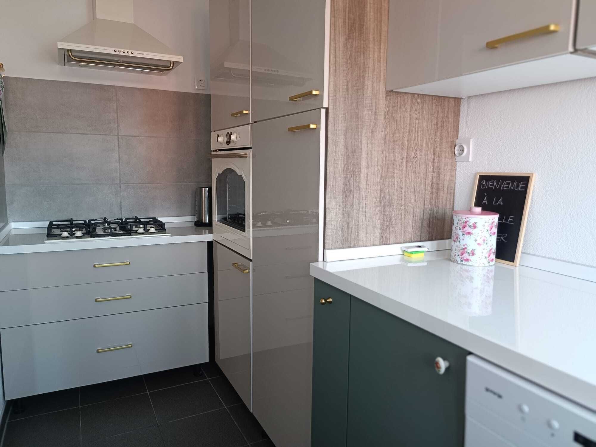 A modern kitchen with a gas stove, oven, and a chalkboard sign.
