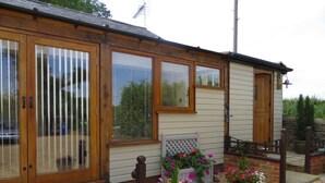 Een huis met een houten gevel, grote schuifdeuren van glas en een grindpad.