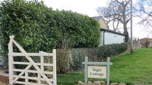 Een huisje met een houten poort, een bord met de tekst 'Yogis Cottage' en een stenen muur.