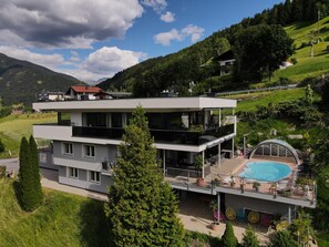 Un edificio moderno de dos pisos con terraza en la azotea y piscina.