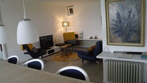 A modern living room with a sofa, chairs, a coffee table, a TV, and a radiator. - Modern 3 bedroom garden apartment with maximum privacy (Castino bei Alba)