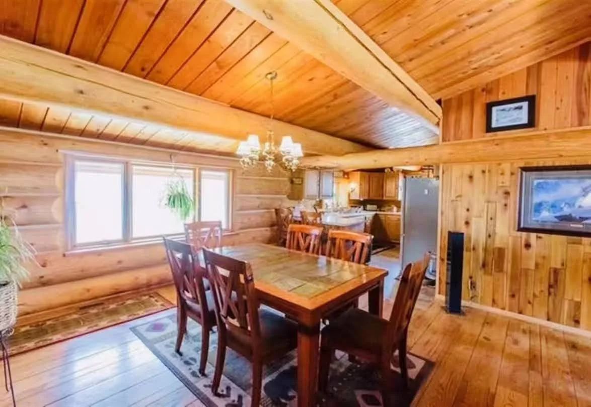Un interior de madera con comedor, cocina y televisor montado.