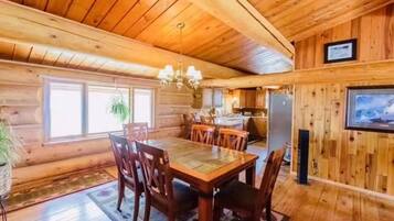 Un interior de madera con comedor, cocina y televisor montado.