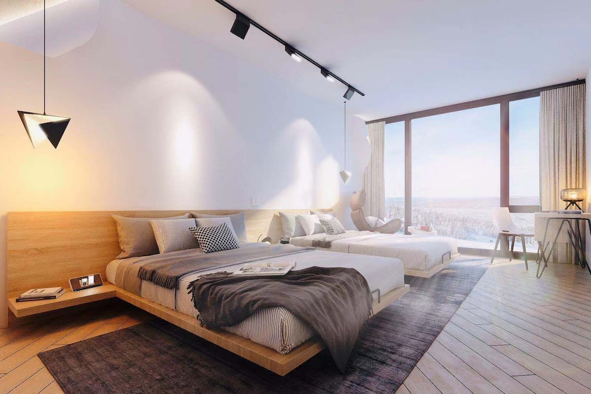 A modern hotel room with a large bed, a desk, and a view of the city.