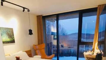 Habitación de hotel moderna con una cama grande, un escritorio y vistas al exterior a través de una puerta corredera.