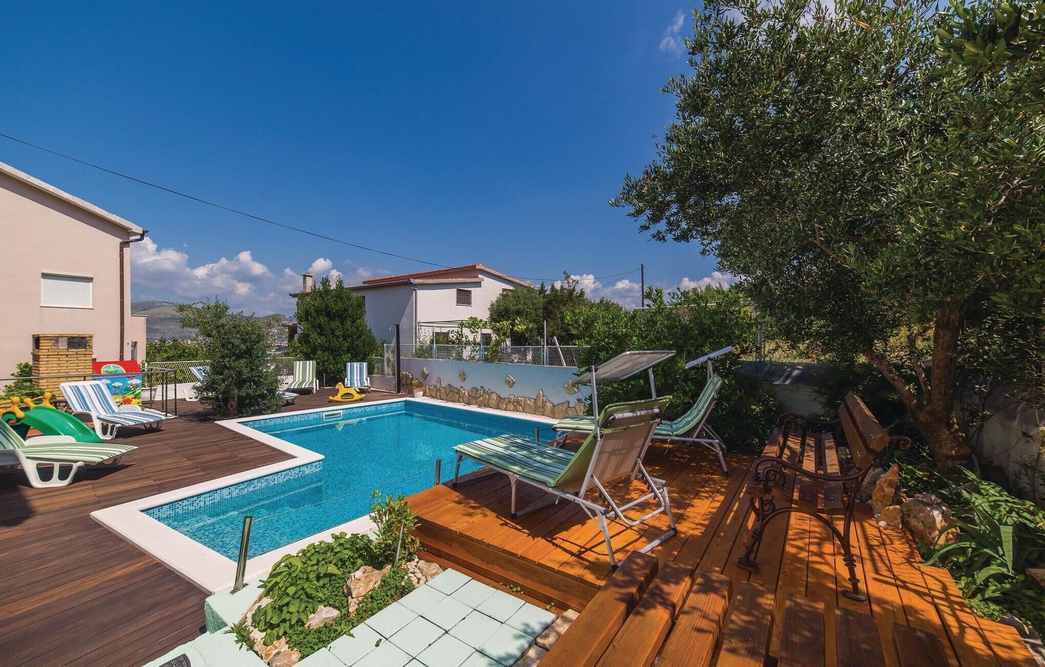 Un pati amb piscina, seients de relax i un pont de fusta.